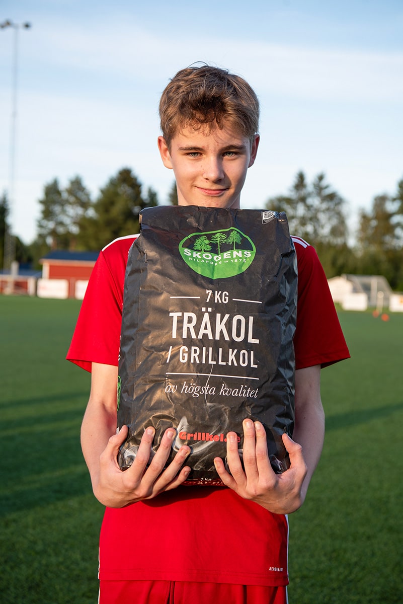 Ung kille med en säck grillkol från Skogens