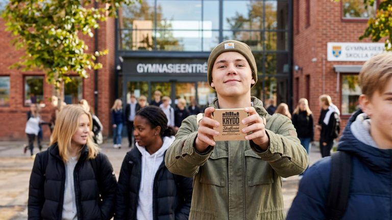 En gymnasie elev står framför skolan och håller fram ett paket saffran.